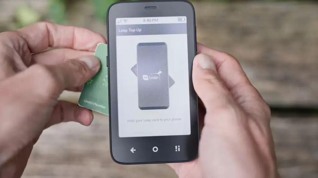 Смартфон в руках, на экране приложение Leap Top-Up с инструкцией „Hold your Leap card to your phone“. Рядом — зелёная транспортная карта Leap, поднесённая к телефону для бесконтактного пополнения через NFC.